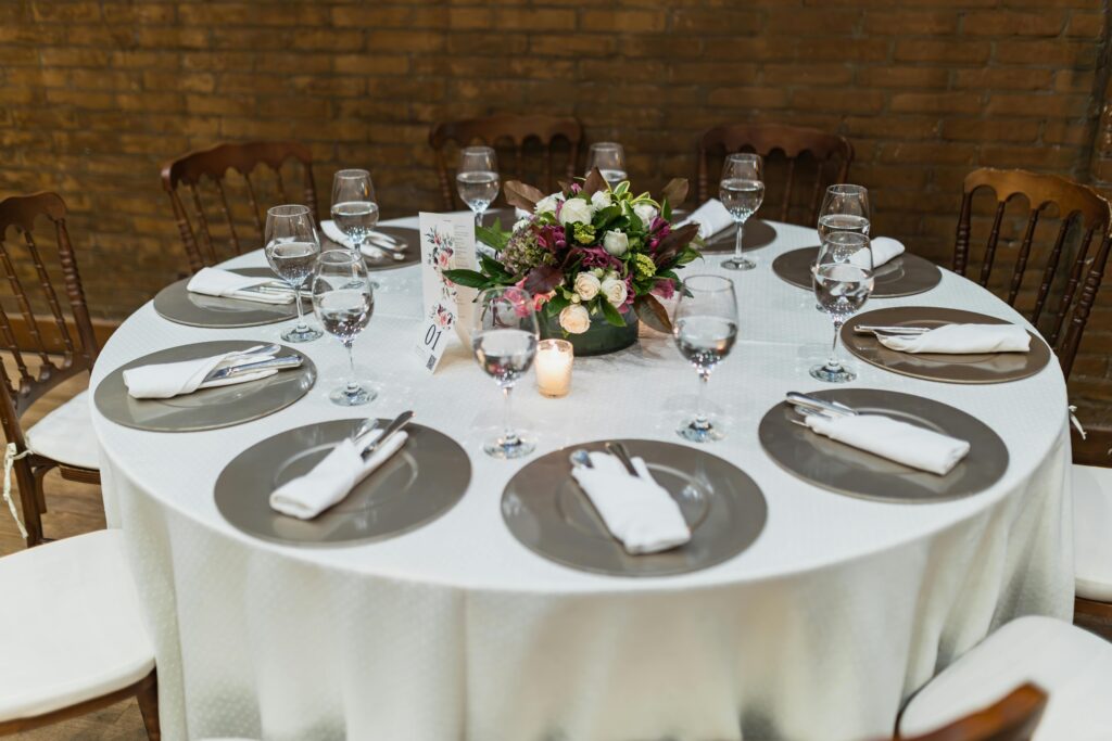 A beautifully set round table with floral centerpiece and candle, perfect for a wedding reception.