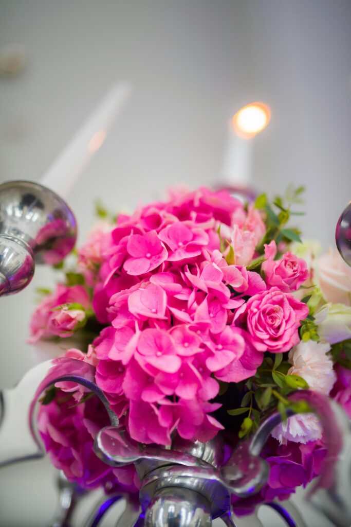 Beautiful floral arrangement with pink hydrangeas and roses adorned with lit candles.